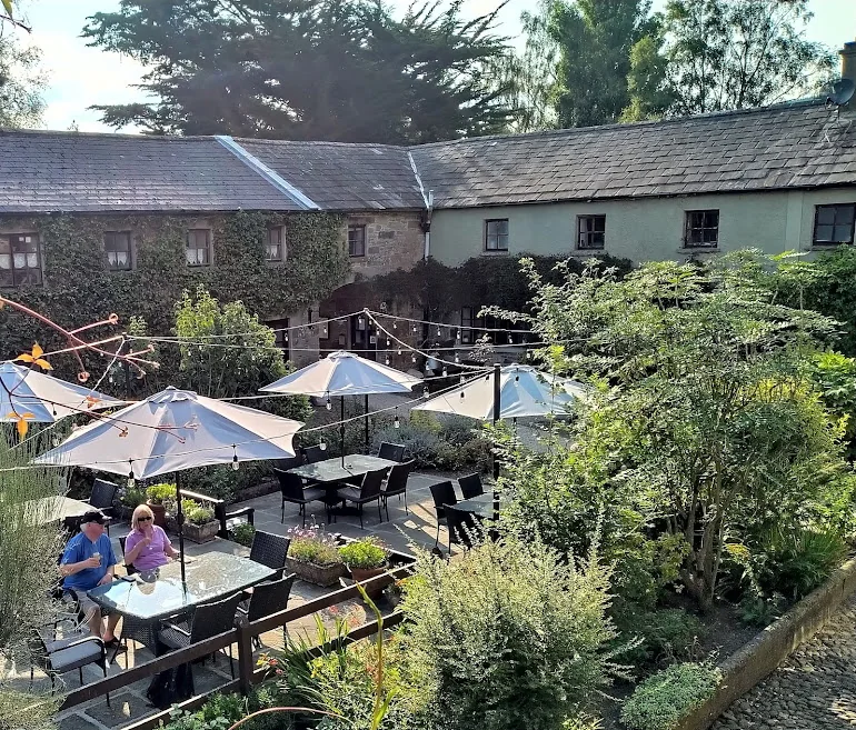 Tables and parasols among flowers in the courtyard of the house
