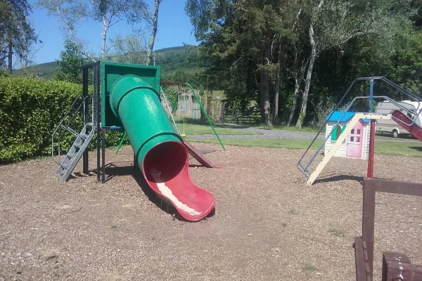 A slide and climbing frame on bark in the playground